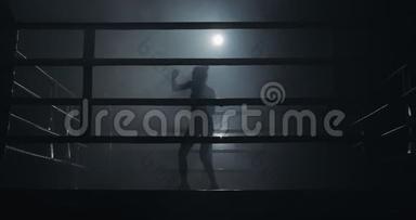 女拳击手在黑暗中训练。 慢动作。 剪影。 拳击概念